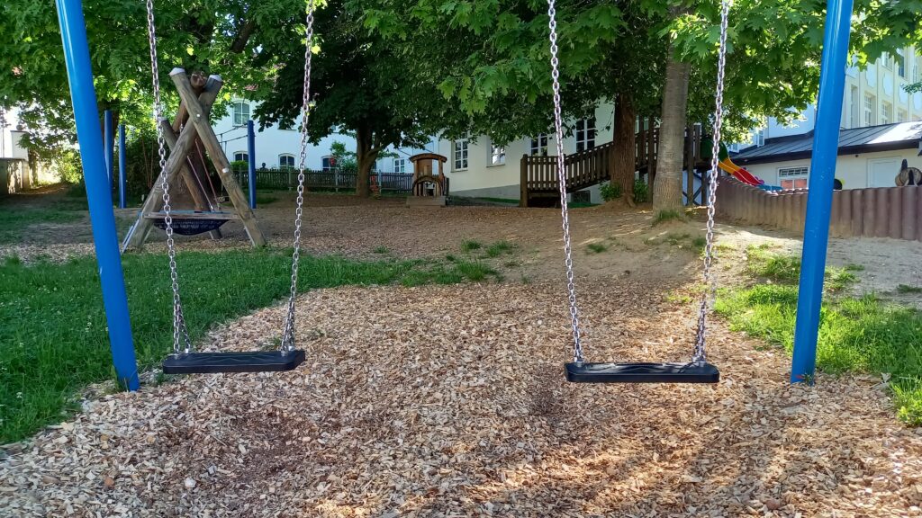 Schaukeln mit Holzmulch auf Spielplatz.