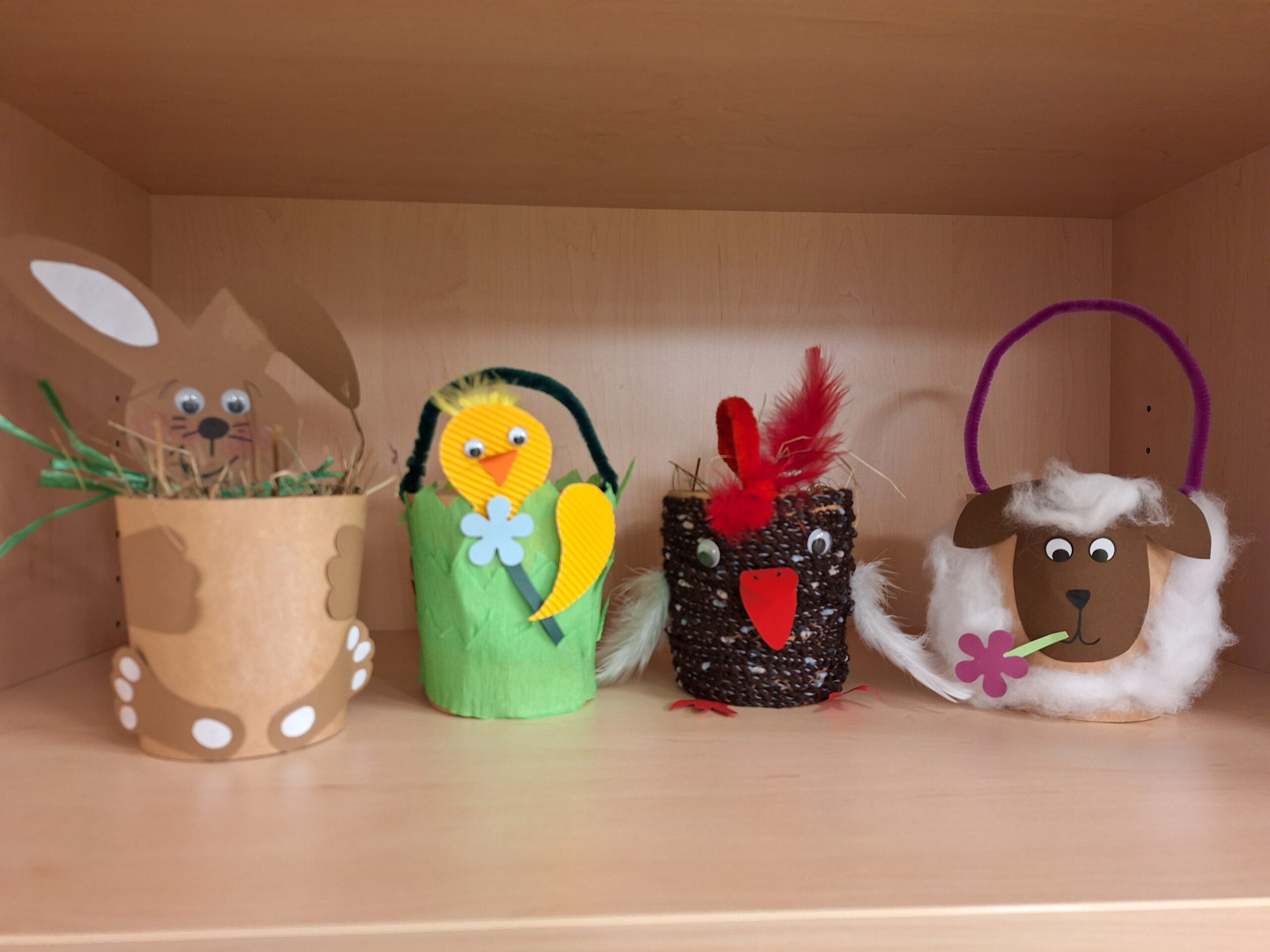 Vier Bastelobjekte auf Regal: Frosch, Huhn, Schneemann und Ei-Ent.