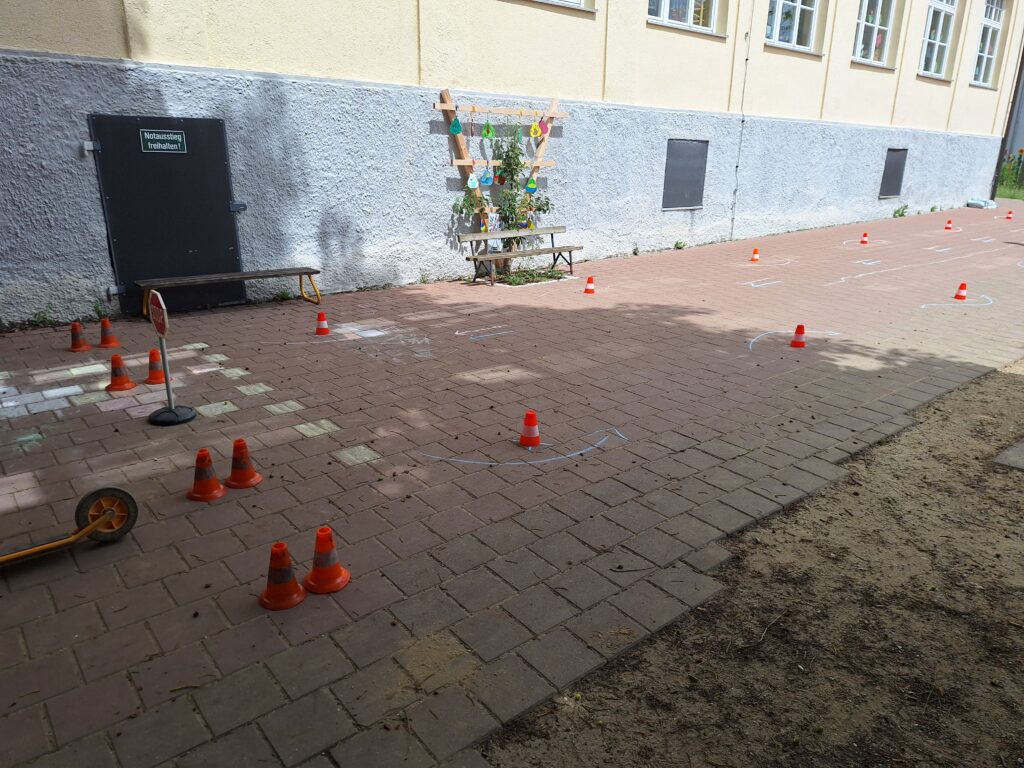 Schülerplatz mit Spielzeughütten, Tretwagen und Sichtungskonfektion auf einem Schulhof.
