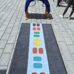 Kleines Spiel im Marktplatz mit bunten Spielsteinen und Bögen auf dem Boden.