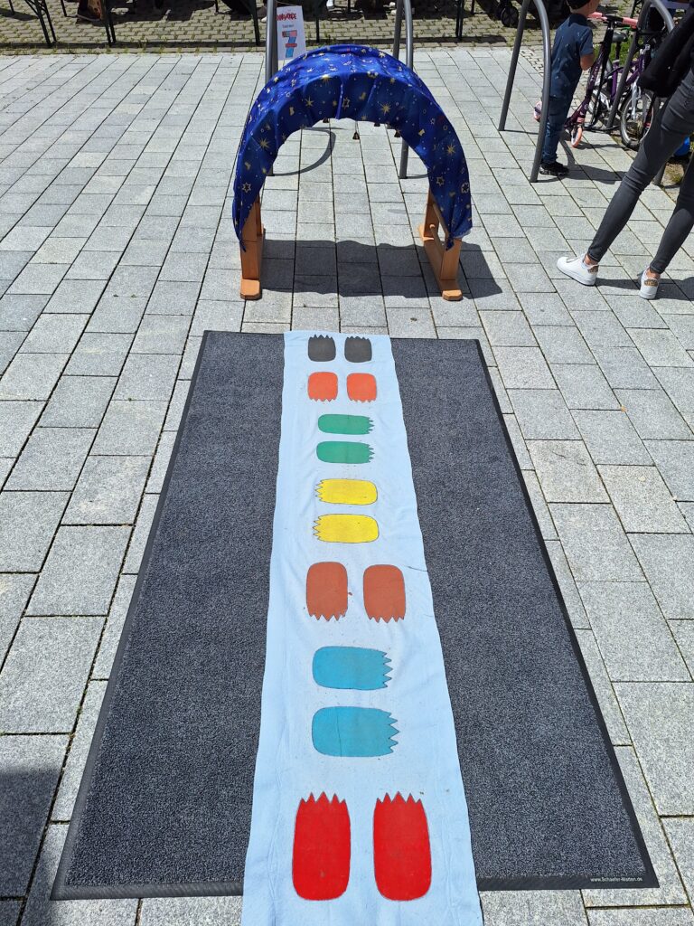 Kleines Spiel im Marktplatz mit bunten Spielsteinen und Bögen auf dem Boden.