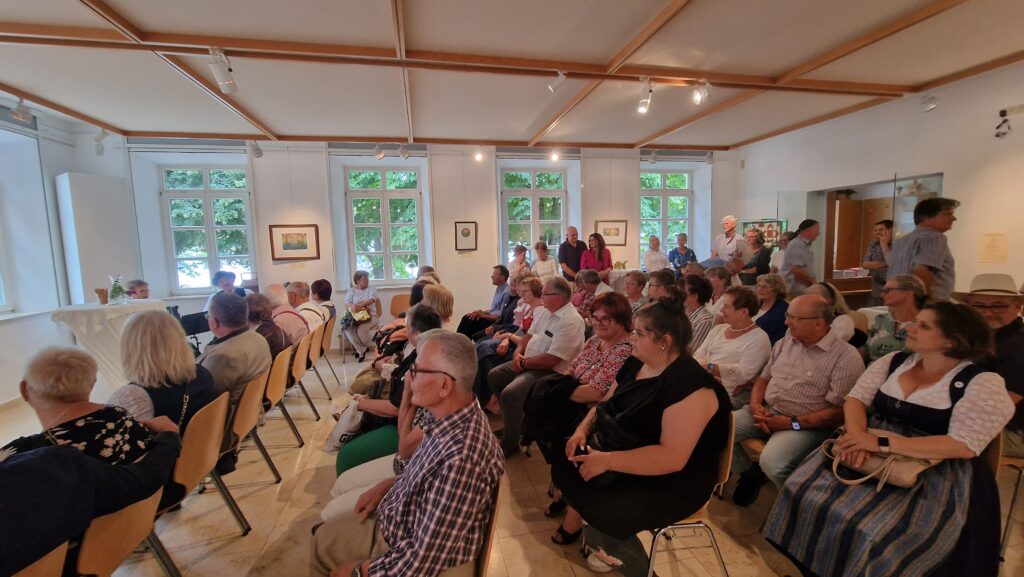 Messe und Kultur in Altomünster – Menschen in einem Raum mit Ausstellung.
