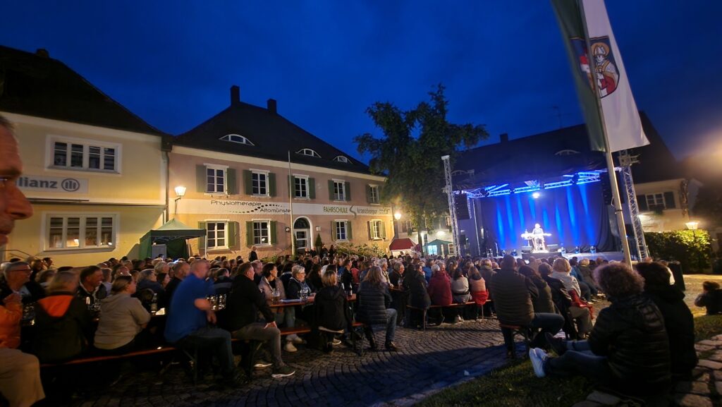 Ein Markt in Altomünster bei Nacht mit Menschen, die an einer Veranstaltung teilnehmen.