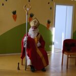 St. Nicholas in buntem Kostüm sitzt im Kinderzimmer.
