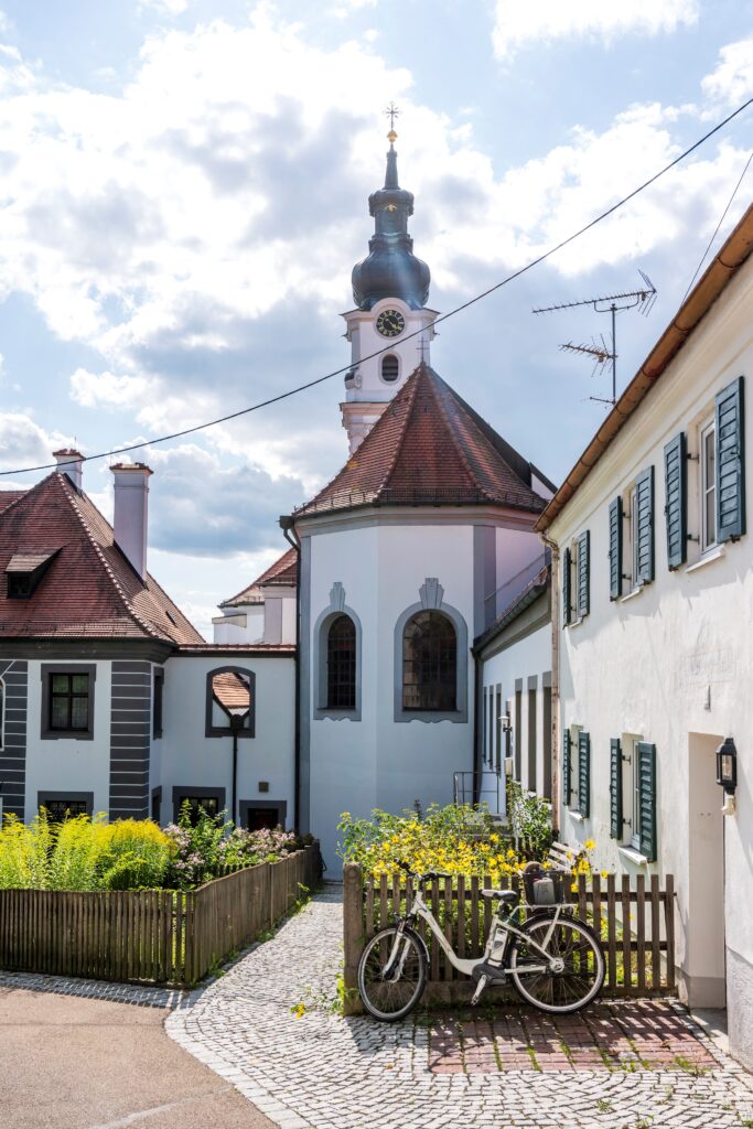Eine Kirche mit Turm und Fahrrad vor einer lichtdurchlassenden Wand.