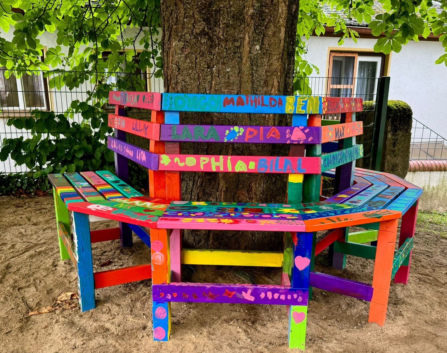 farbige, benutzte Parkbank mit Namen von Kindern auf den Sitzplätzen.