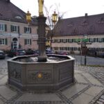 Fußpflichte mit goldenem Statue und Straßenlaternen im Marktplatz Altomünster.