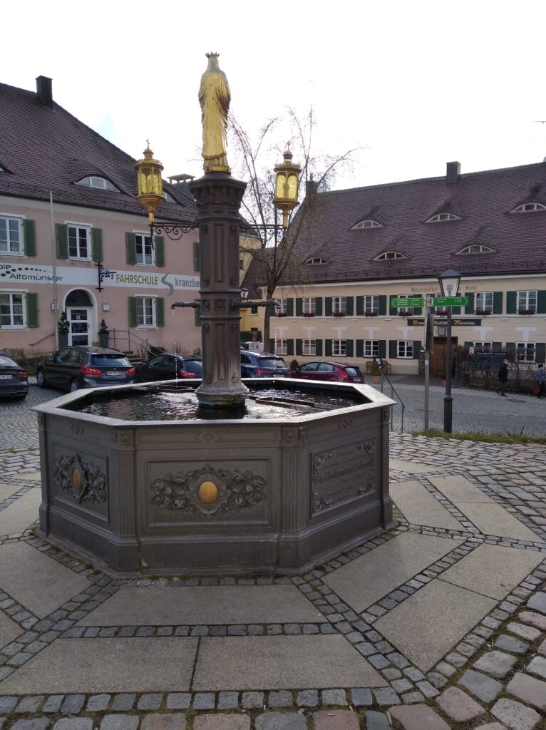 Fußpflichte mit goldenem Statue und Straßenlaternen im Marktplatz Altomünster.