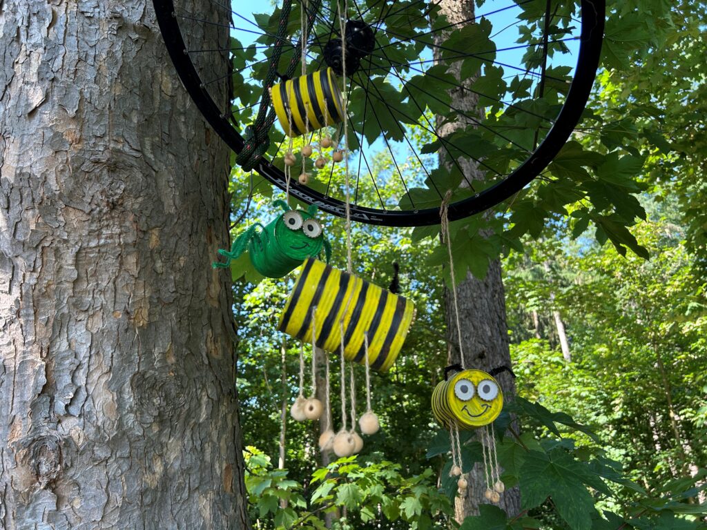 Bienen aus Kunststoff und Kaffeebecher an einem Baumstamm.