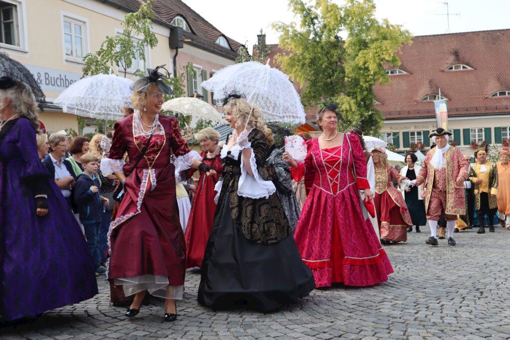 Traditioneller Markt mit Menschen in historischen Kostümen auf Stein.