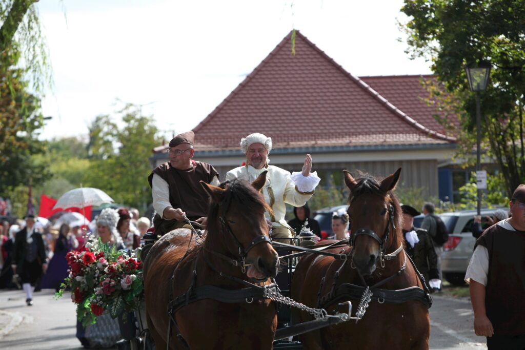 Fahrzeuge mit Pferden in historischen Kostümen auf einem Markt in Altomünster.