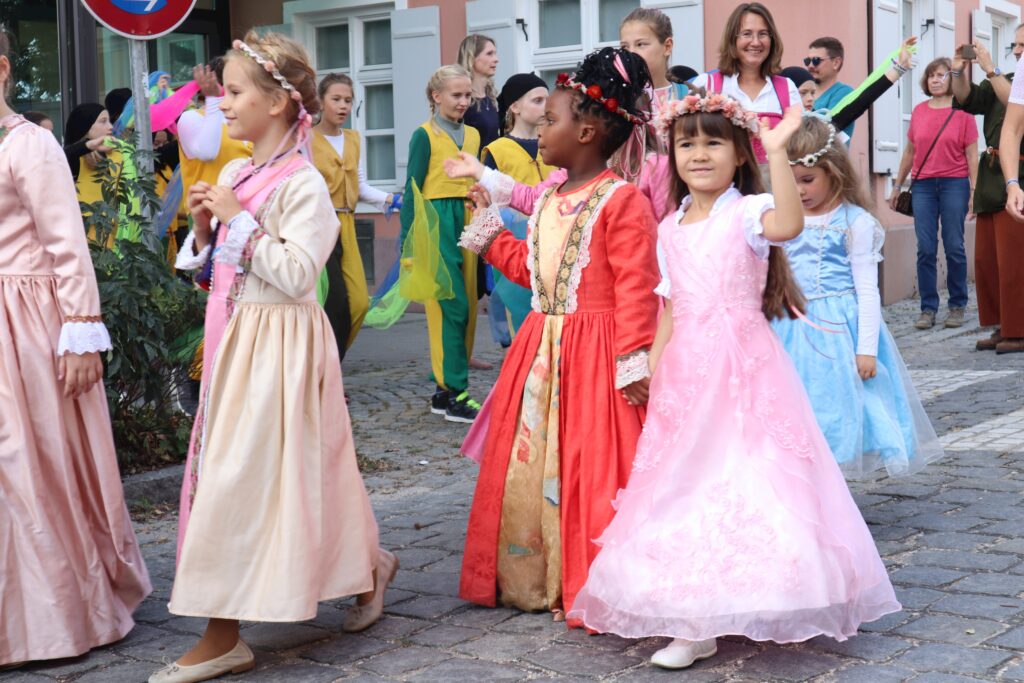Kinder in bunten Kostümen auf einer Marktplatzfahrt.
