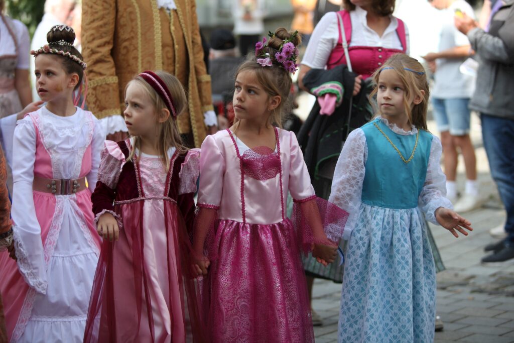 Fotografie von vier Mädchen in historischen Kostümen auf einer Marktstraße.