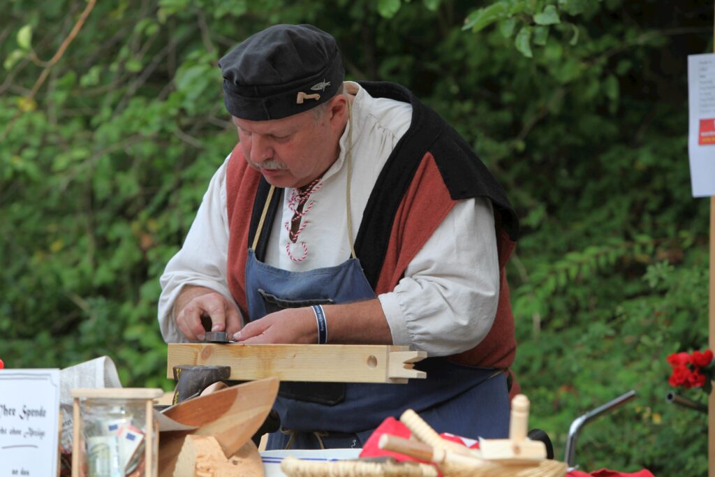 Männlicher Arbeiter mit Hütchen beim Schneiden von Holz.