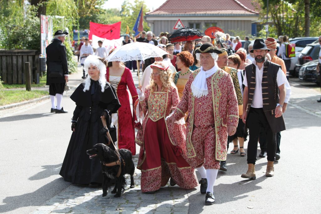 Eine Parade in Altomünster mit historischen Kostümen und einem Hund.