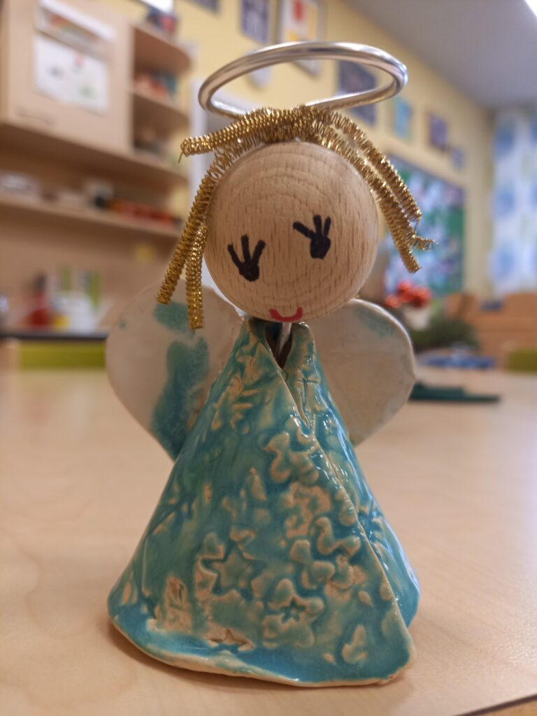 Keramik Engel mit blauem Gewand und goldenem Ring auf Tisch.