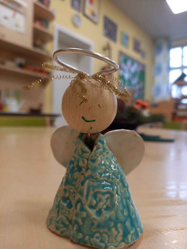 Holzangelt mit glasigem Körper und goldener Schleife auf der Stirn.