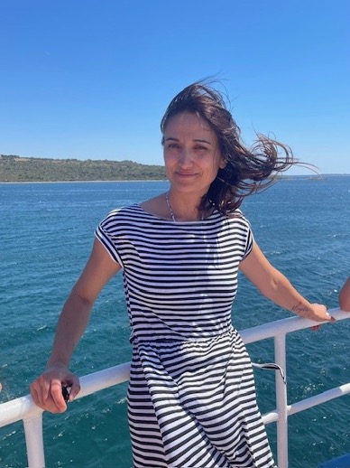 Frau auf Schiff im Strandhintergrund.