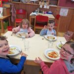Vier Kinder beim gemeinsamen Essen in einer Schule.