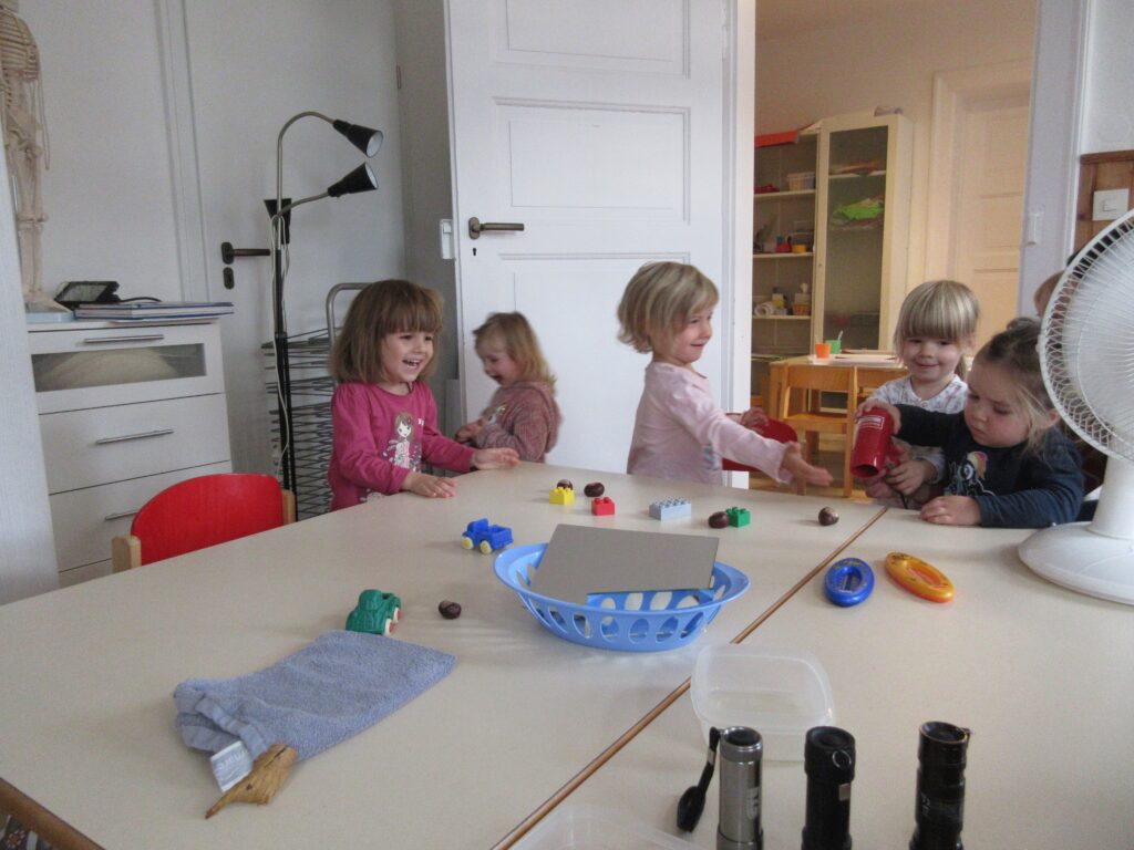 Kinder beim Spielen mit Spielzeug auf einem Tisch in einem Kinderzimmer.