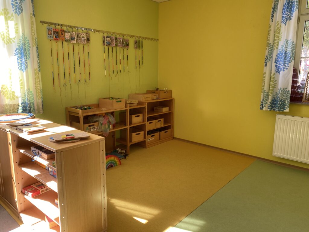 Kinderzimmer mit gelben Wänden, Spielzeug und Schreibtisch.