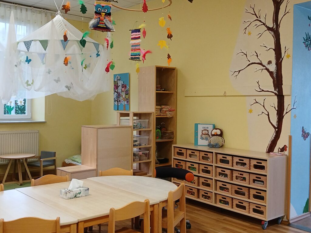 Kleinkinderzimmer mit Spiel- und Ablagegegenständen, Regalen und Schreibtisch.