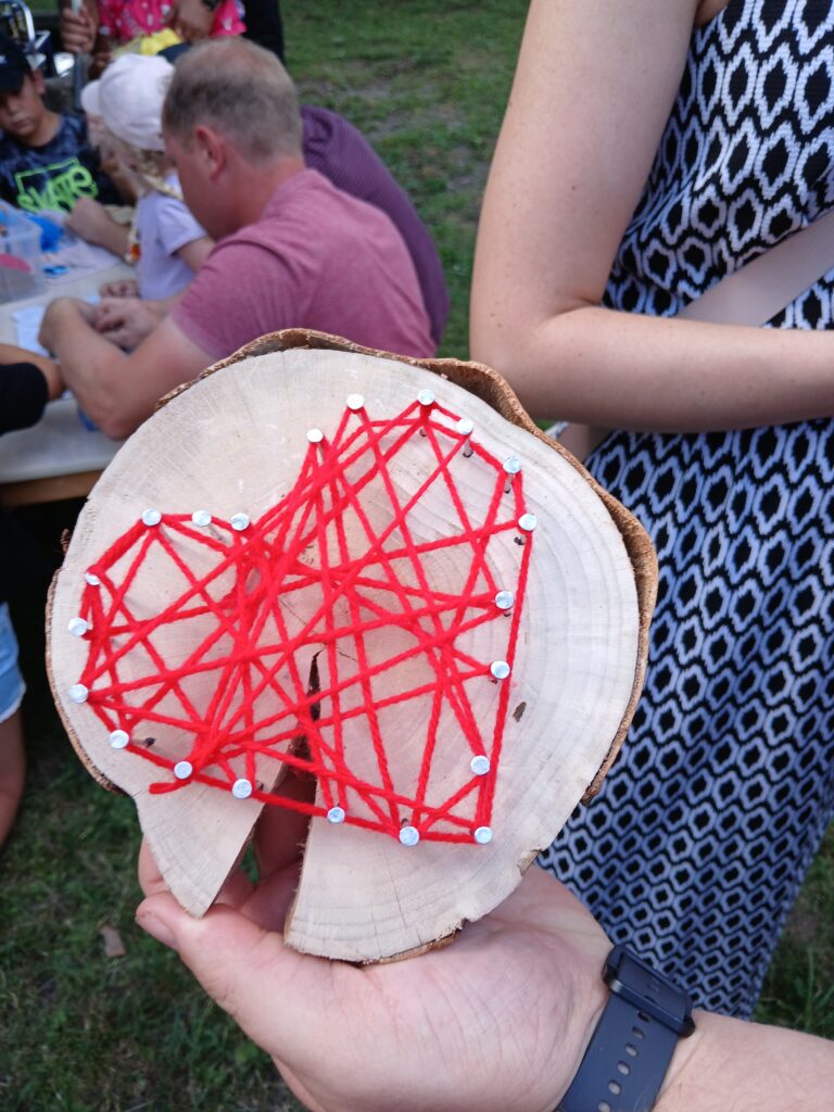 Kreatives Stringart-Malerei auf Baumstückscheibe.