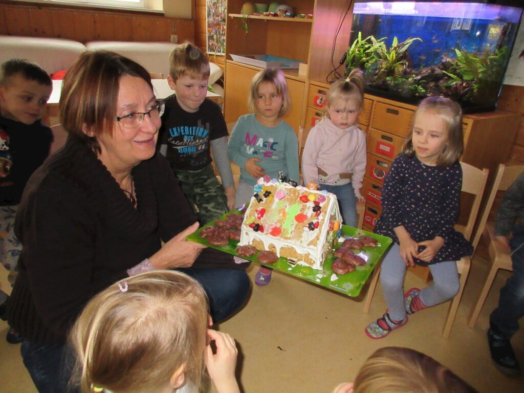 Gärtnerin präsentiert Weihnachtsgebäude vor Kindern in der Kita.