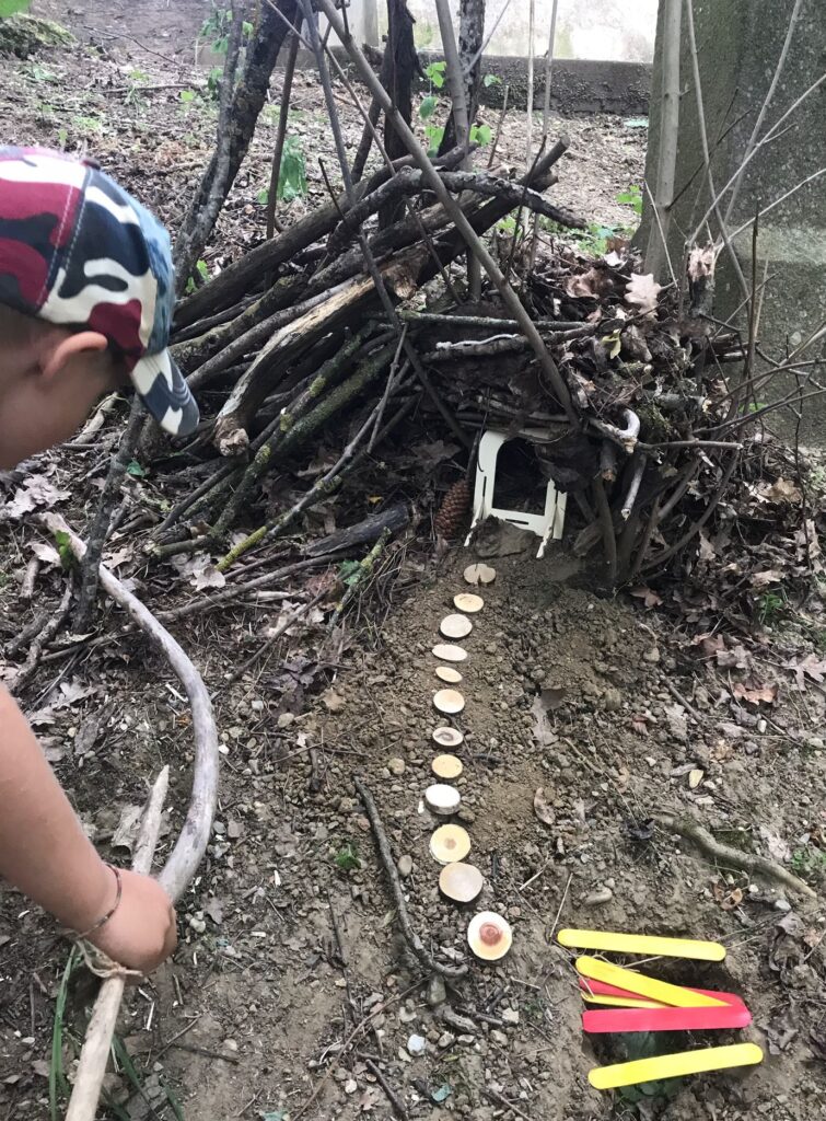 Kind bei Waldwiese, bastelt mit Holz und Steinen.