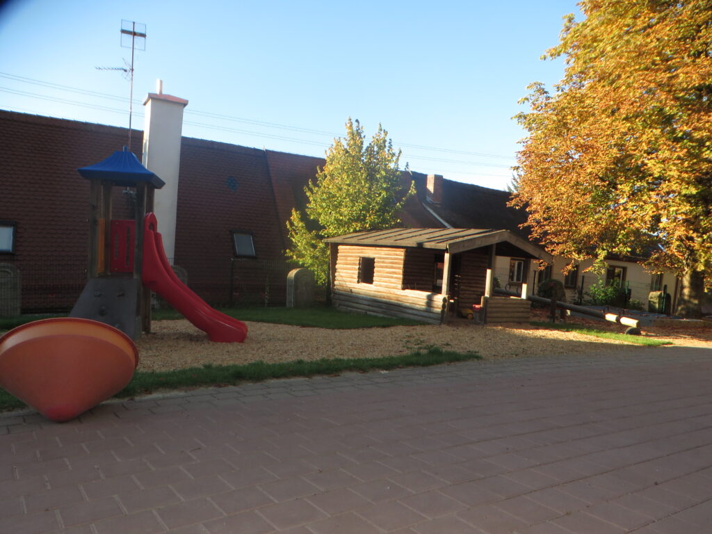 Park mit Spielplatz und Holzgebäude im Herbst.