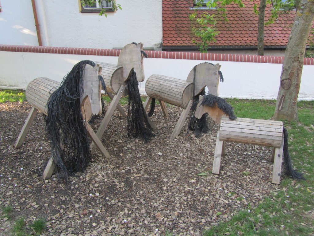 Vier Holzpony mit geflochtenen Haaren im Garten.