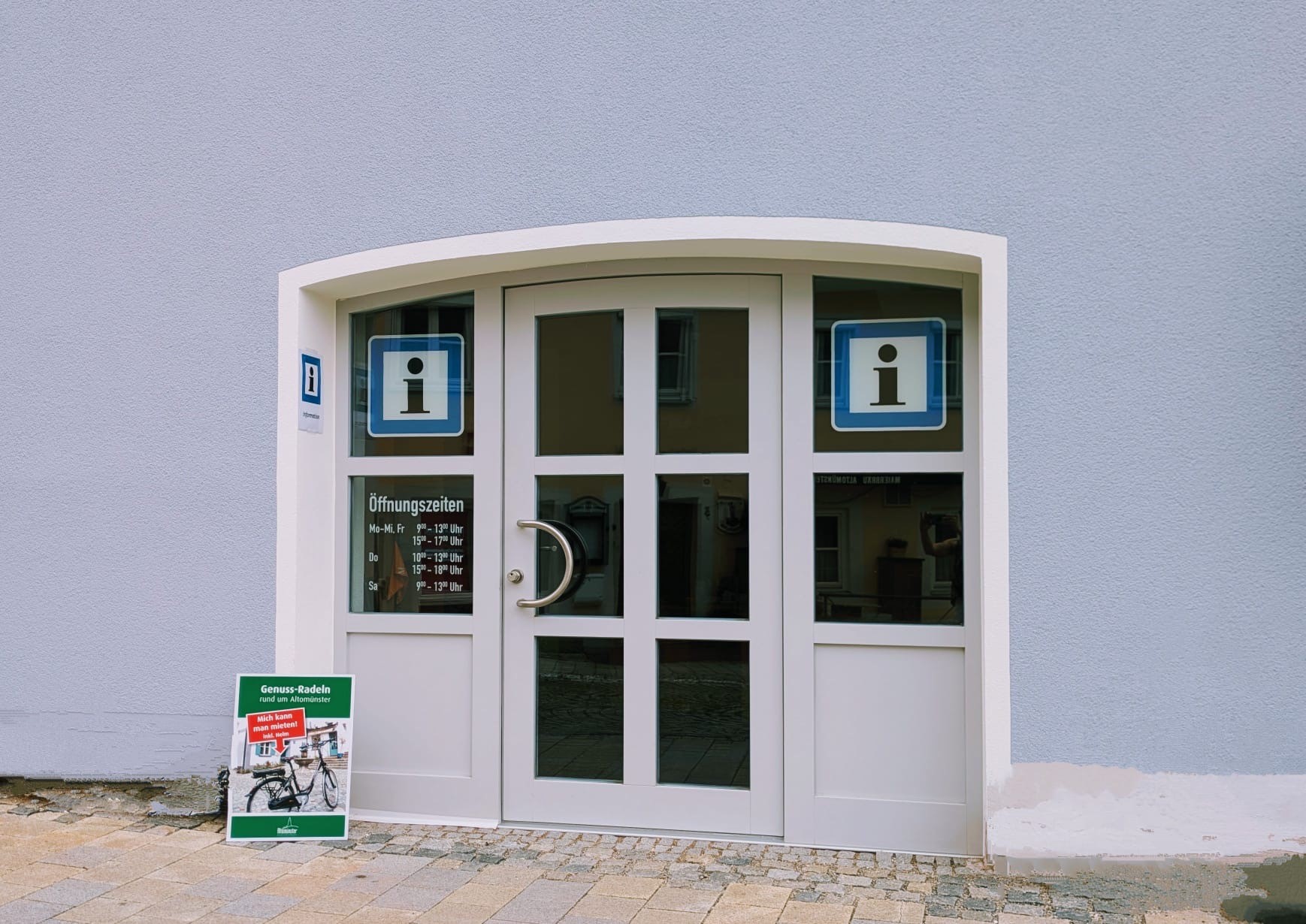 Infobüro Eingangsbereich zum Marktfachgeschäft Altomünster. Öffnungszeiten und Informationszeichen an der Tür.