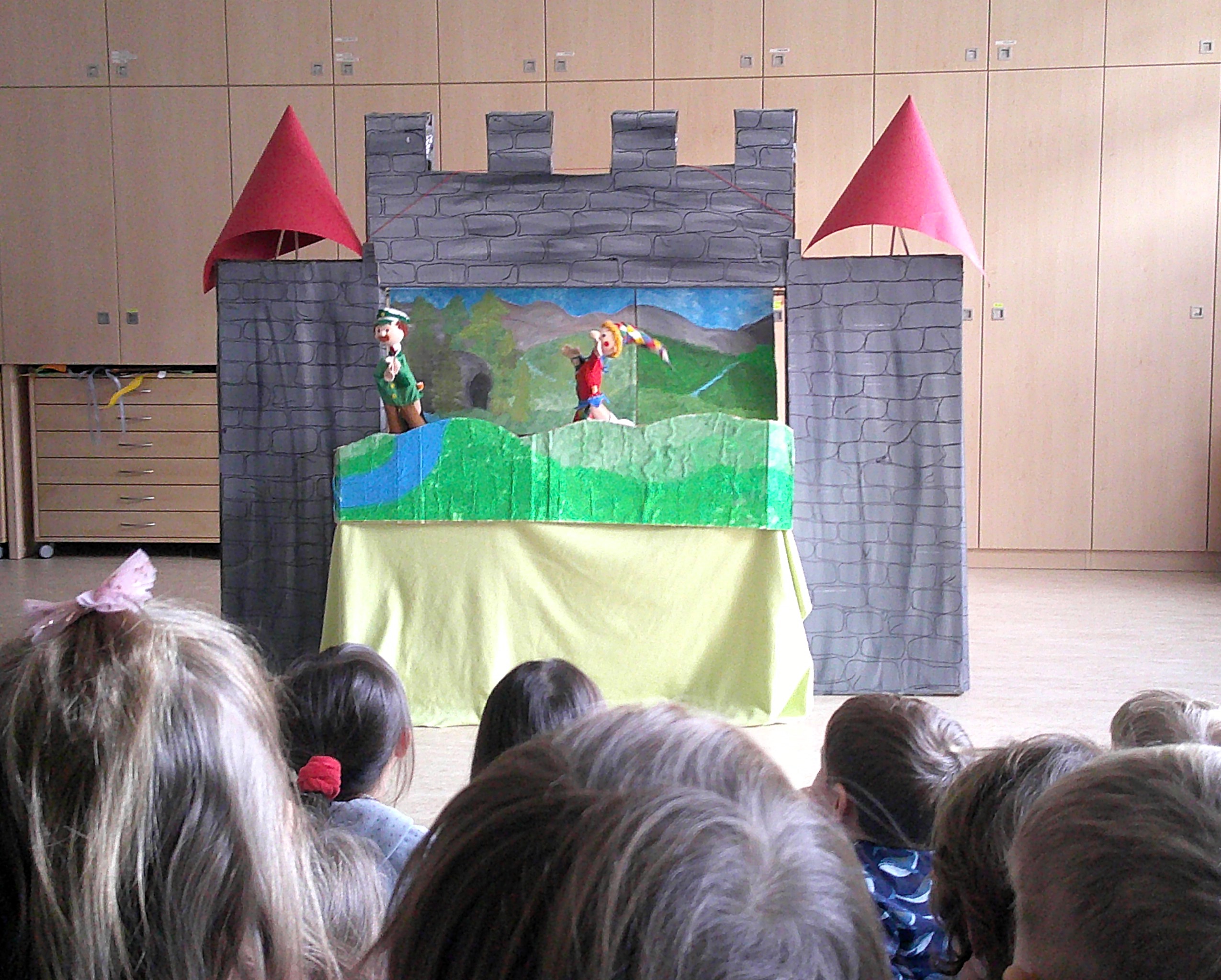 Puppenvorstellung in einem Spielhaus mit einer Zeichnung von einem Kastell und zwei Figuren auf dem Podium für Kinder.