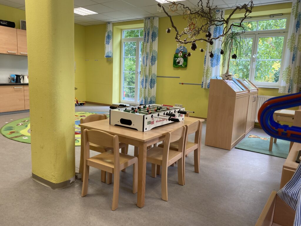 Kinderzimmer mit Kicker, hellen Wänden und Spielwaren.