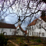 Markt Altomünster mit Kirche und Garten vor bewölktem Himmel.