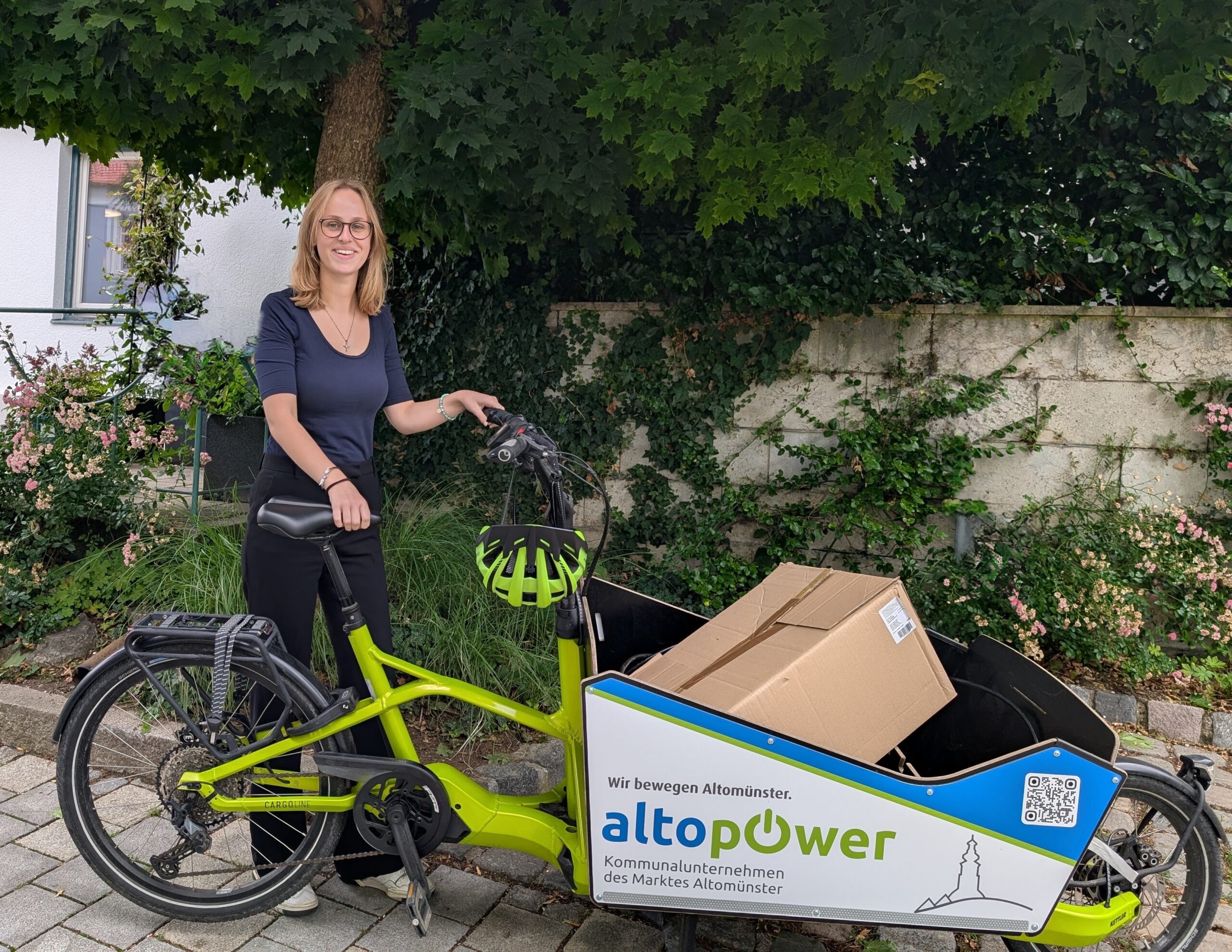 Frau mit Elektrorad und Paket auf der Fahrt, Altomünster.