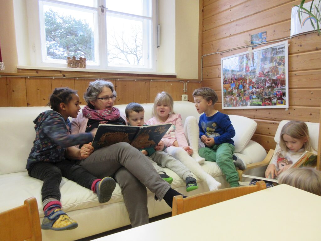 Mutter und Kinder lesen gemeinsam auf dem Sofa.