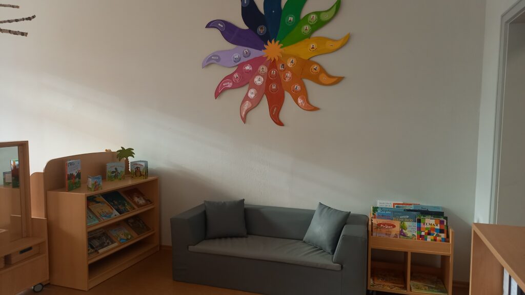 Ein Raum mit Sofa, Buchregalen und buntem Wanddekor.