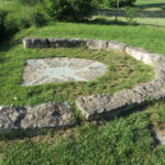 Landschaft mit Steinring und Mosaik auf Gras.