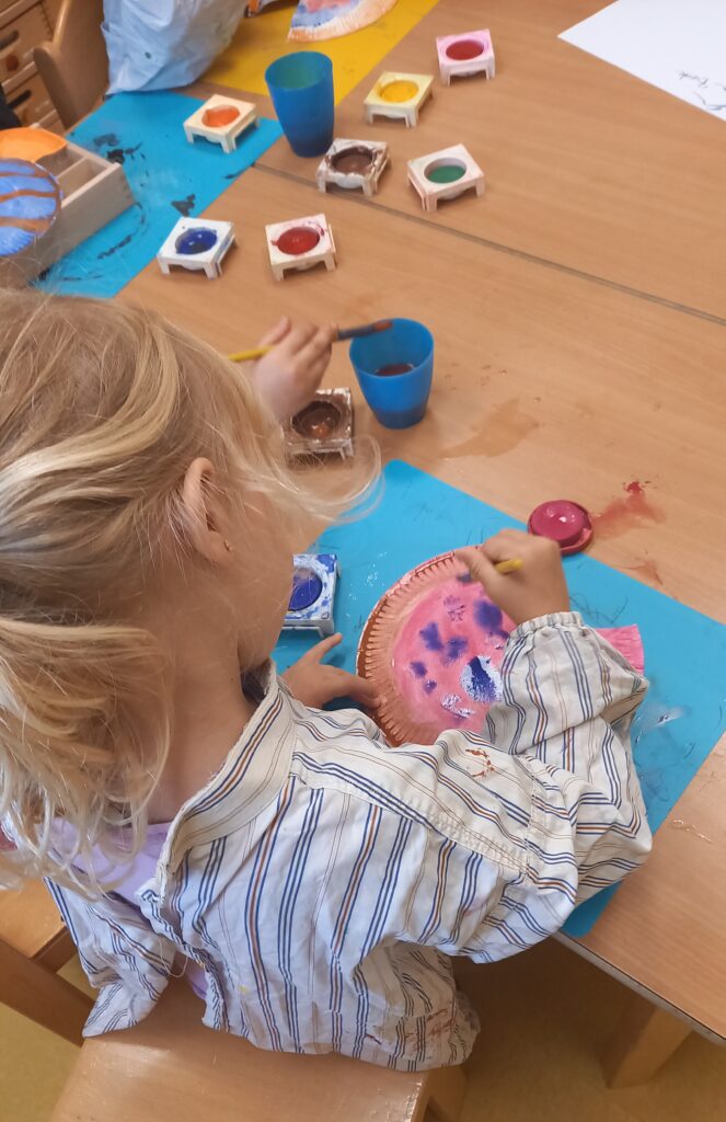 Kleinkind malt auf Papier mit Farben in einem Kinderbrettstil.