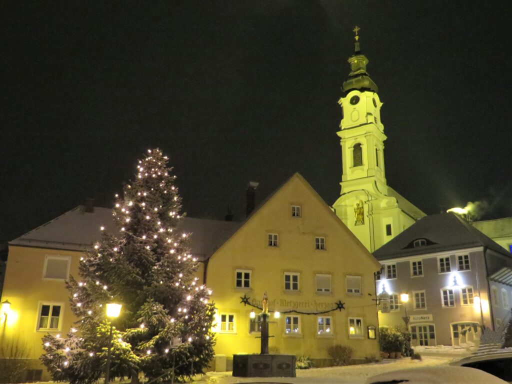 Weihnachtsmarkt in Altomünster, beleuchtete Kirche und Christbaum im Winter.