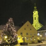 Weihnachtsmarkt in Altomünster, beleuchtete Kirche und Christbaum im Winter.