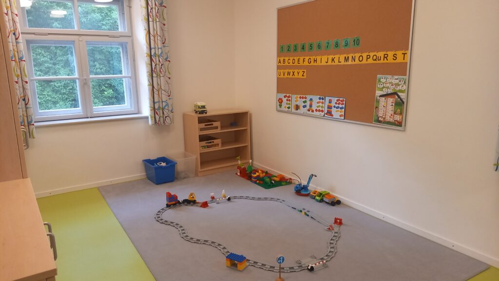 Kinderzimmer mit Spielzeug, Trainingsbahn und Alphabet.