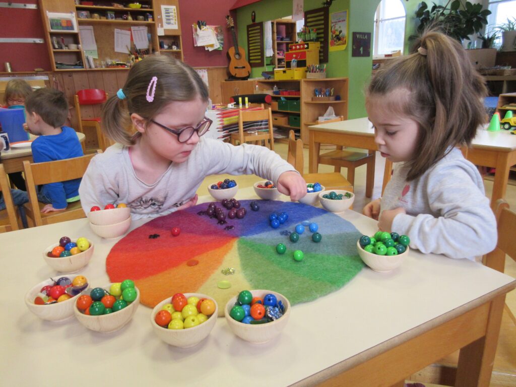 Zwei Kinder spielen mit bunten Kugeln auf einem farbigen Raster in einer Kindergärtnerei.