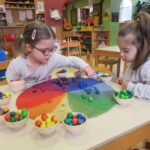 Zwei Kinder spielen mit bunten Kugeln auf einem farbigen Raster in einer Kindergärtnerei.