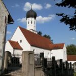 Kirche Altomünster mit Turm und rotem Dach, umgeben von einem Zaun.