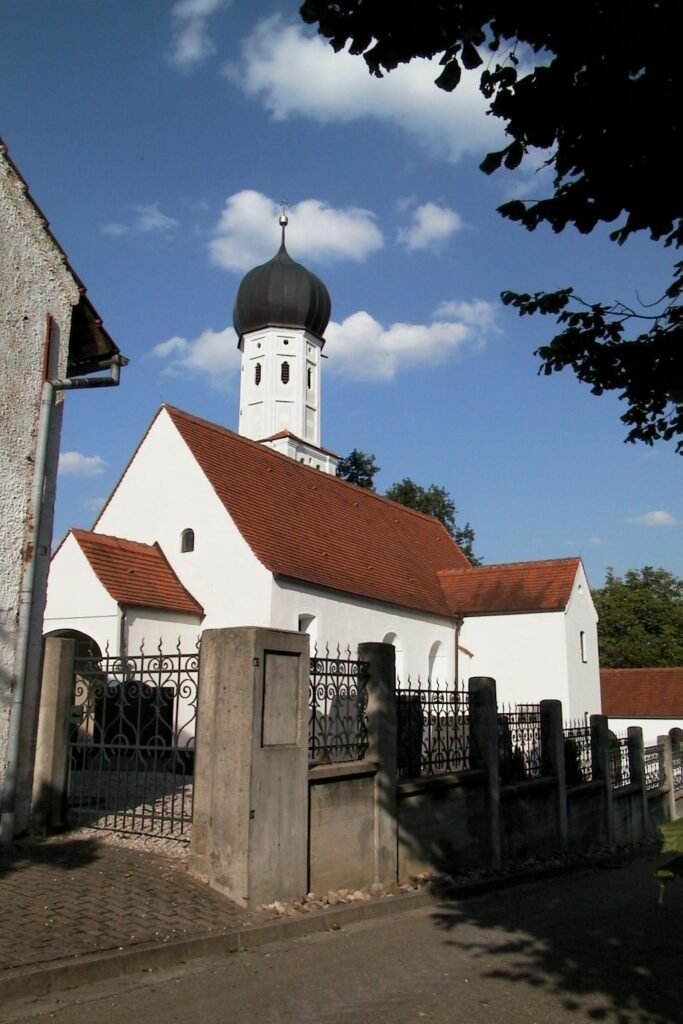 Kirche Altomünster mit Turm und rotem Dach, umgeben von einem Zaun.