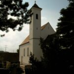 Kirche Altomünster, Gebäude mit Turm und Schutz, umgeben von Bäumen und Gras.