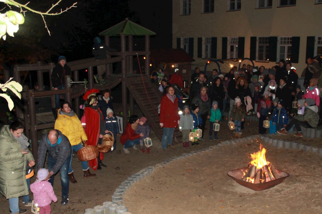 Ein Kinderspielplatz bei Nacht mit Lichtern und Feuer im Sand.
