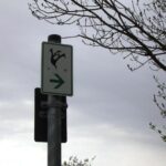 Schild mit Schauriges-Weg und Pfeil nach rechts. Baumwurzeln im Hintergrund.